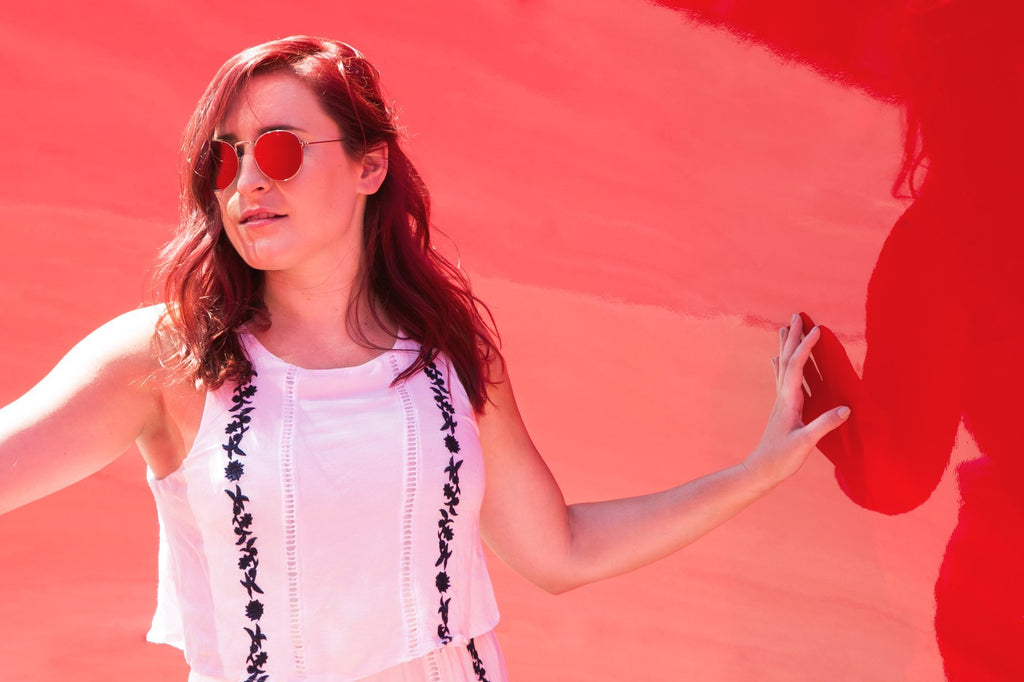 woman wearing subtle floral top against a red background
